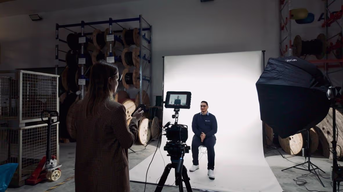 Studioaufnahmen behind the scenes mit Frau hinter der Kamera und einem Mann auf einem Hocker sitzend
